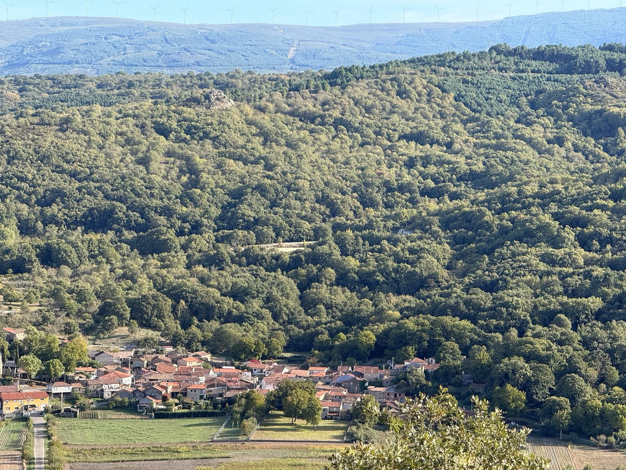 O pobo ao pé do monte, coas leiras diante e os muíños de vento no cumio do fondo